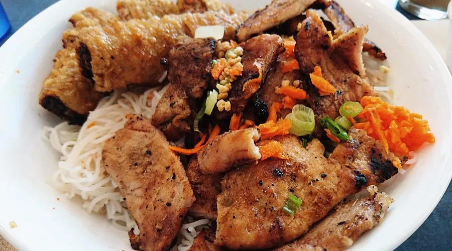 Grilled lemongrass BBQ chicken over vermicelli noodles with fresh herbs