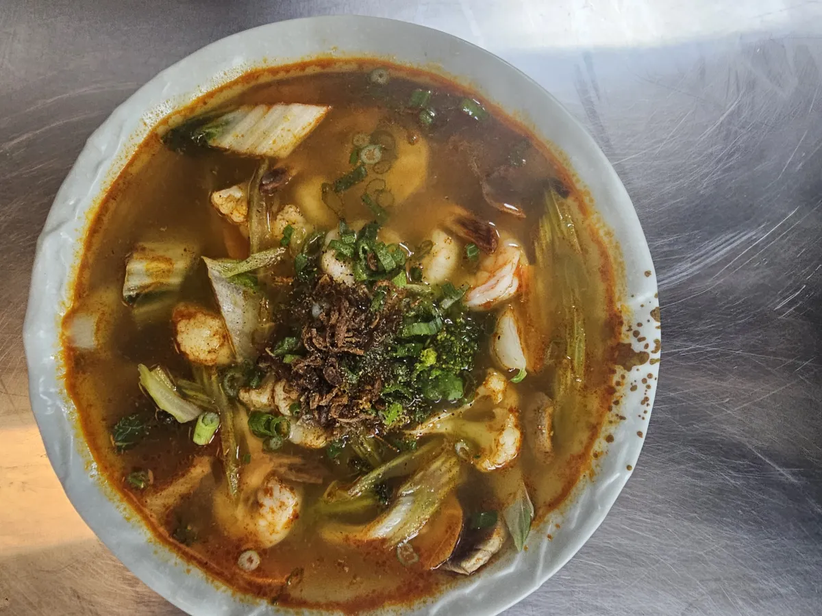 A bowl of Thai Tom Yum rice noodle soup with shrimp, mushrooms, and herbs